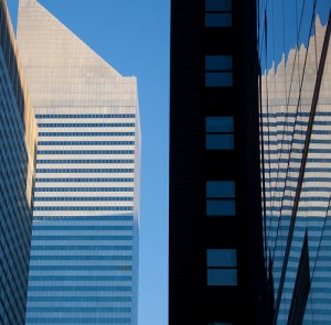 A real skyscraper, and its distorted reflection created by the windows of a nearby skyscraper.