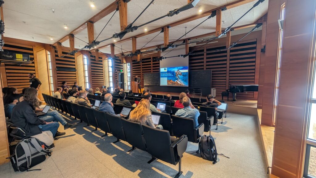 An audience listening to the beginning of a presentation at a conference.