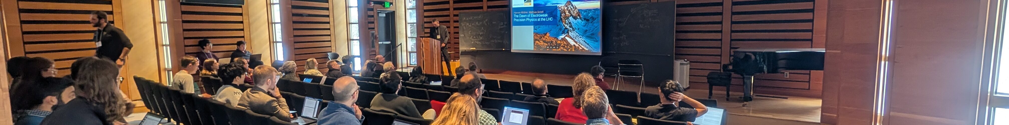 An audience listening to the beginning of a presentation at a conference.