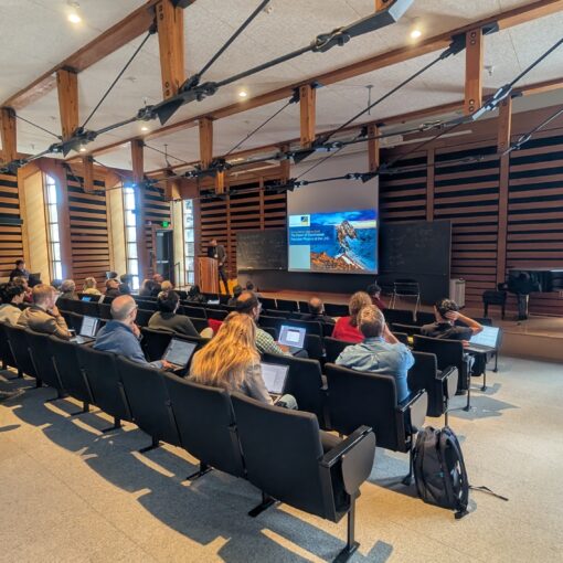 An audience listening to the beginning of a presentation at a conference.