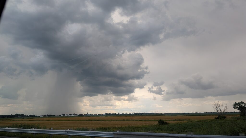 Rain is seen falling in the distance as we pass into a region with mixed weather.