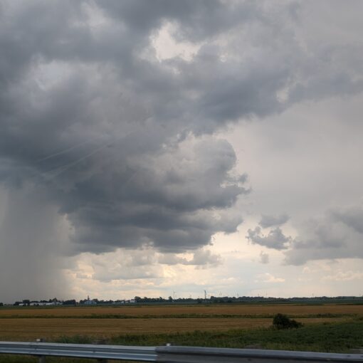 Rain is seen falling in the distance as we pass into a region with mixed weather.