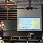 A person standing on a stage presenting a slide deck.